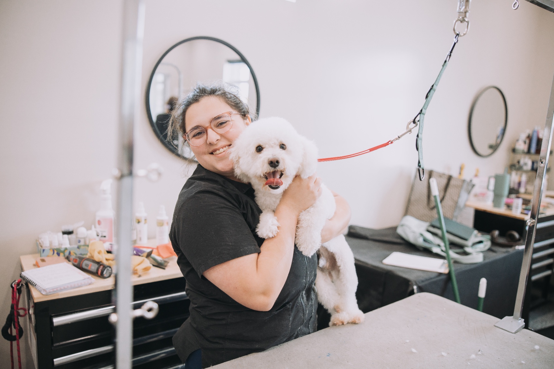 Groomer hugging a freshly trimmed pup at the table